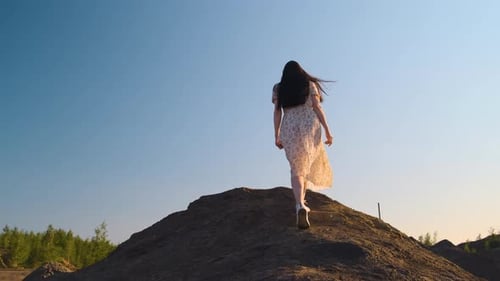 Beautiful Woman in Light Wind Blown Dress Climbs Hiking Peak and Very Happy About It Throws Her Arms