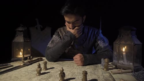 Man Moves Chess Pieces on Map Table in Dark