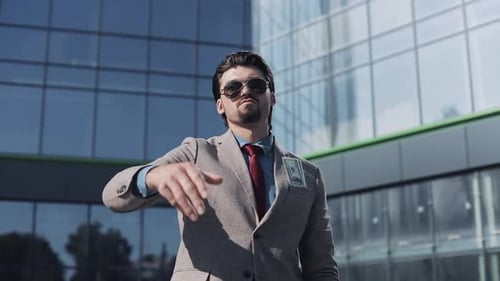Young Successful Businessman in a Suit Wear Sunglasses Throwing Money in the Camera Standing