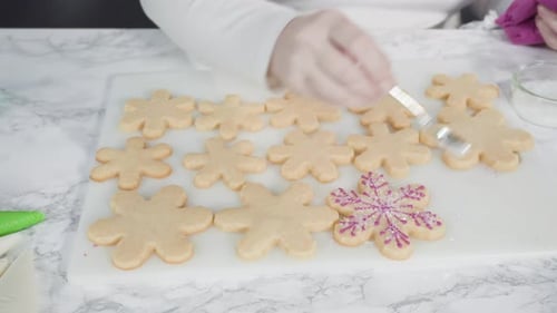 Step by step. Icing snowflake shaped sugar cookies with pink royal icing.