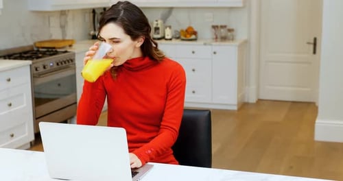 Woman Working on Laptop and Drinking Juice