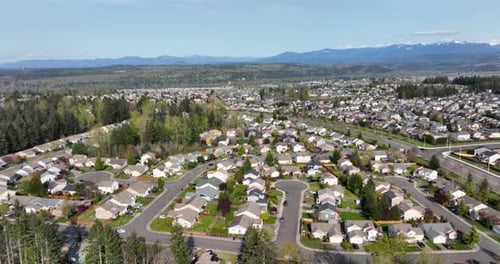 Panning aerial revealing a multitude of houses living beneath Mt. Rainier.
