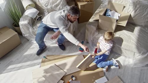 Father and Son Assembling Furniture in House