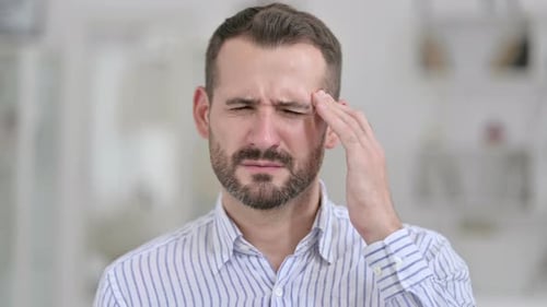 Man Experiencing Severe Headache Rubbing Temples