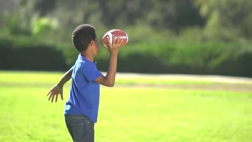 Boy and Man Playing Football in the Park