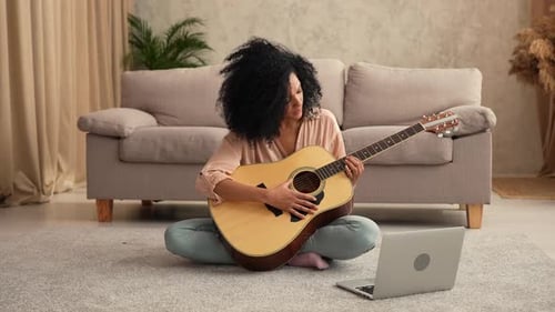 Young Woman Plays Guitar at Home