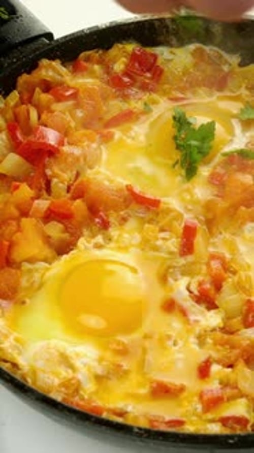 Close Up Cooking Shakshuka with Eggs and Herbs