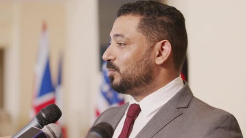 Man Speaks at Press Conference with Flags