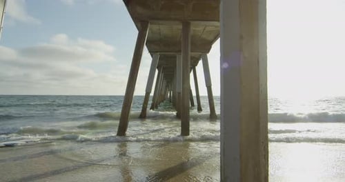 Sea waves reaching the beach under a pier