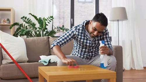 Man Cleaning Table in Living Room with Spray