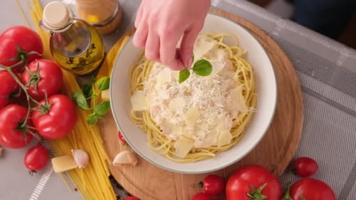 Making Pasta Carbonara Pouring Fresh Basil to Parmesan Cheese Spaghetti Ceramic Dish