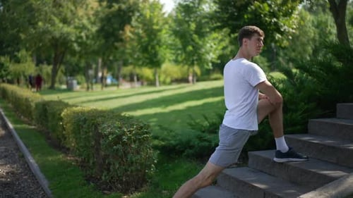Side View Young Man Stretching Leg Muscles in Slow Motion Outdoors