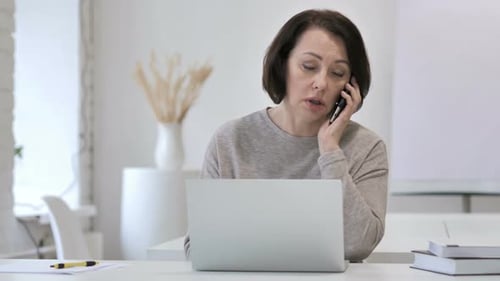 Woman Talking on Phone While Using Laptop