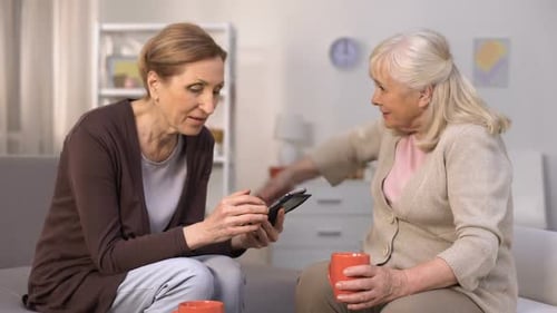 Two Mature Women with a Smartphone Indoors