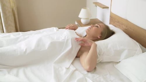 Woman Wakes Up and Stretches in Bed