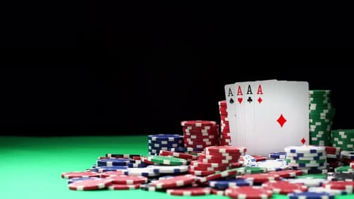 Four Aces in the Middle of Poker Chips in Stacks Lying on a Green Table
