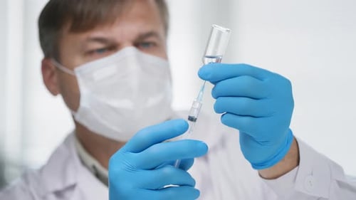 Doctor Draws Vaccine From Vial With Syringe