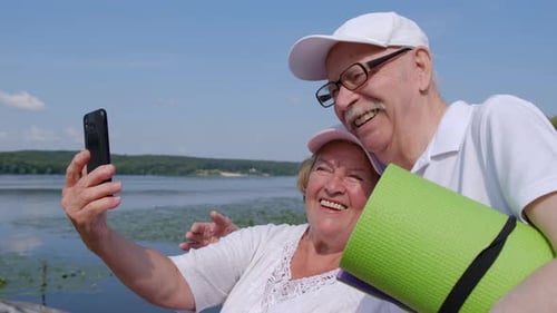 Smiling Senior Couple Take Selfie by Lake