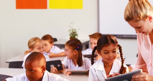 Teacher Helping Students with Tablets in Classroom