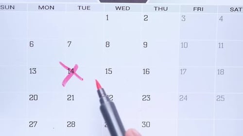 Hand Crossing off Dates on Calendar with Red Marker