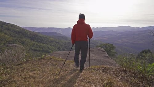 An Asian tourist hiker hiking or trekking on trail on mountain hill. Outdoor landscape