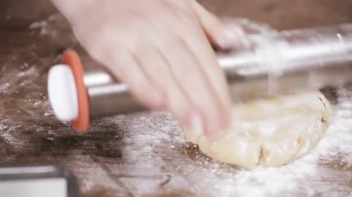 Rolling Pin Flattening Dough on Flour Covered Surface