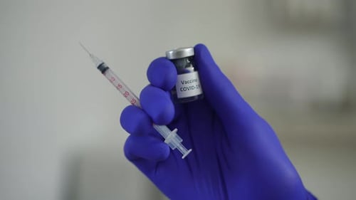 Closeup Hand in Blue Medical Glove with Syringe and Covid19 Vaccine Jab