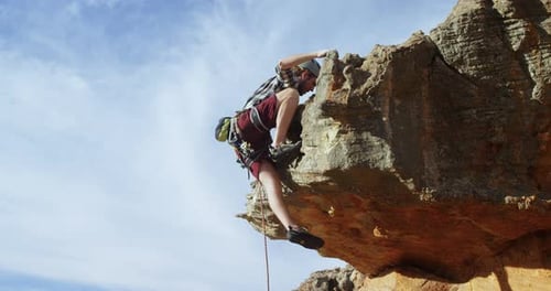 Mountaineer climbing on the hill with the help of rope