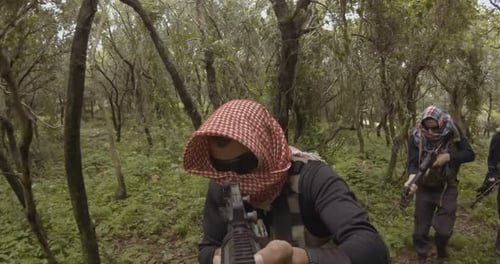 POV footage of armed terrorists patrolling a forest area