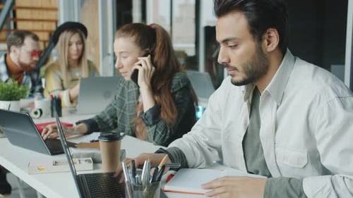 Diverse Group of Businesspeople Working in Shared Office Using Laptops and Talking on Mobile Phone
