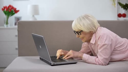 Senior Woman Using Laptop on Couch