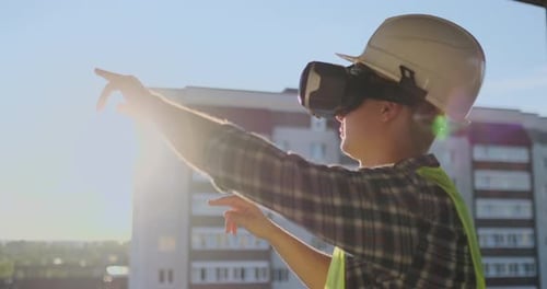 Engineer Builder Visualizes the Building Plan Standing on the Roof of the Building at Sunset Stands