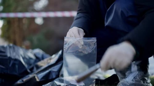 Investigator collects knife into evidence bag at crime scene