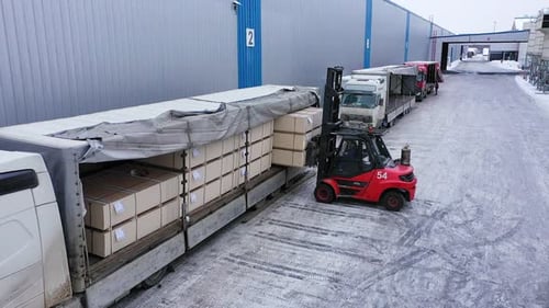 Una cargadora está cargando paquetes de aglomerado en el camión de la fábrica