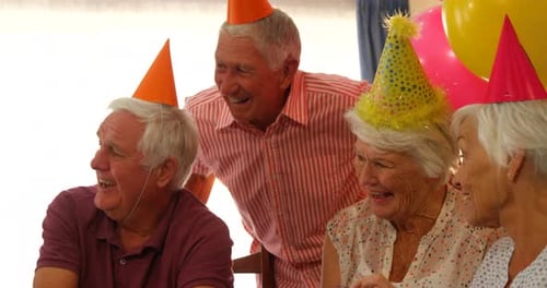 Cheerful Seniors Celebrate Birthday with Hats and Gifts