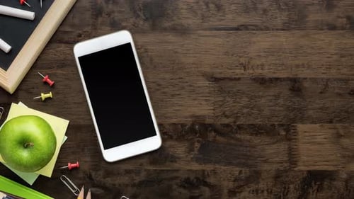 Fournitures scolaires et smartphone avec écran vide sur fond de table en bois brun foncé