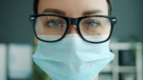 Close-up of Attractive Female Doctor Wearing Glasses and Medical Mask Indoors