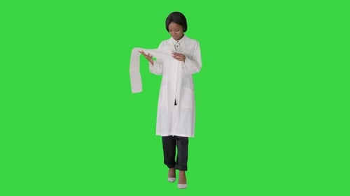 Smiling African American Female Doctor Reading Cardiogram on a Green Screen, Chroma Key.