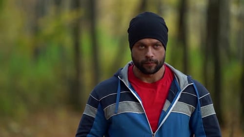 Bärtiger Hipster-Mann geht am Herbsttag allein im Wald spazieren, mittleres Porträt eines Wanderers oder Backpackers