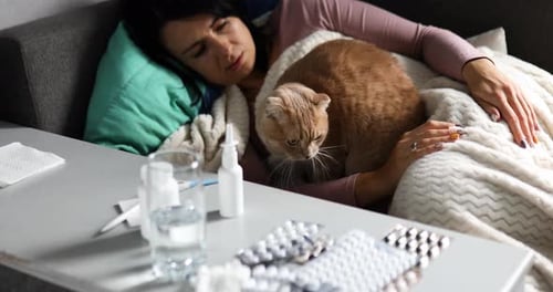 Sick Woman Lying on the Sofa with Cat at Home