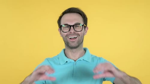 Happy Man Making Heart Sign on Yellow Background