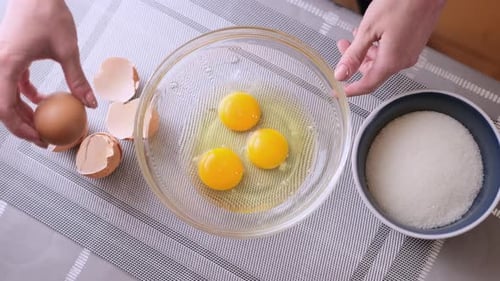 Une femme écrase des œufs dans un bol en verre et fait de la pâte