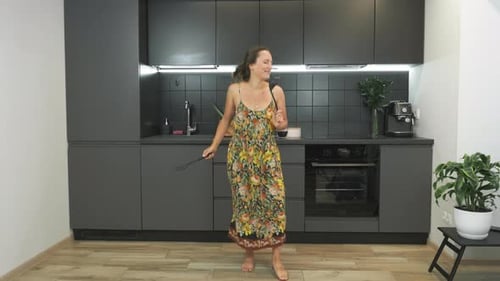 Woman Dances Singing in Modern Kitchen Interior