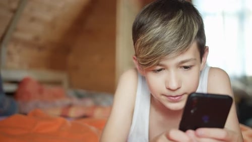Teenager Lies in Bed Using Smartphone