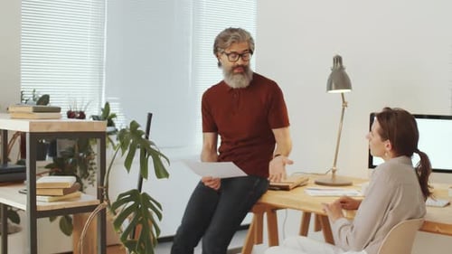 Man Discussing Documents with Woman in Office
