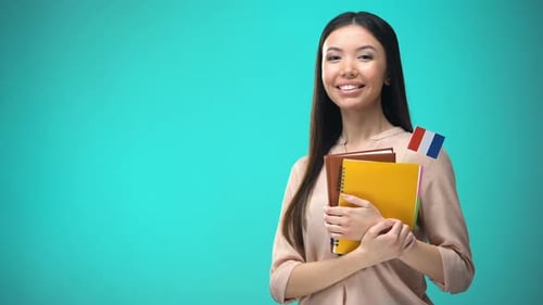 Femme joyeuse tenant le drapeau français livre, éducation à l'étranger, apprentissage de la langue