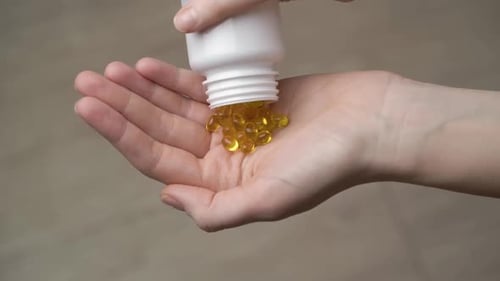 Vitamin Omega-3 or Vitamin D in a female hand close-up.