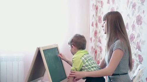 Mom Helps Son to Draw the Sun on the Board