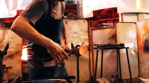 Glassblower Shaping Hot Glass in Workshop