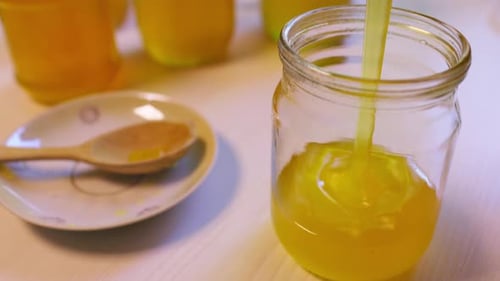 Pouring Golden Honey Into a Jar